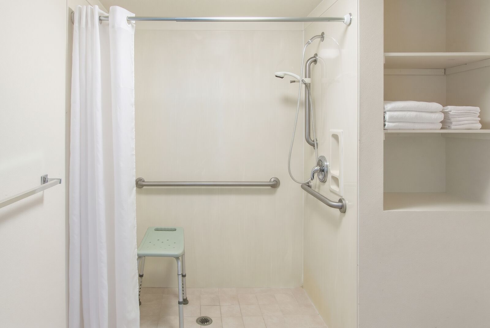 Accessible roll-in shower with grab bars and a shower bench